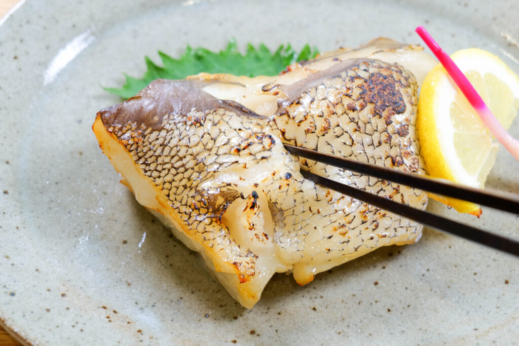 箸で銀むつカマ味噌漬け焼きを割ろうとしている様子。皮目の焼き色と身のふっくら感が伝わる