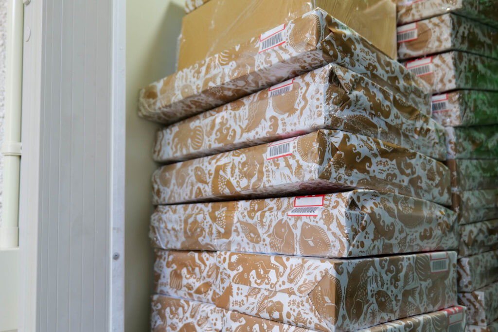 魚政の店舗で山積みにされた発送待ちのお歳暮ギフト箱