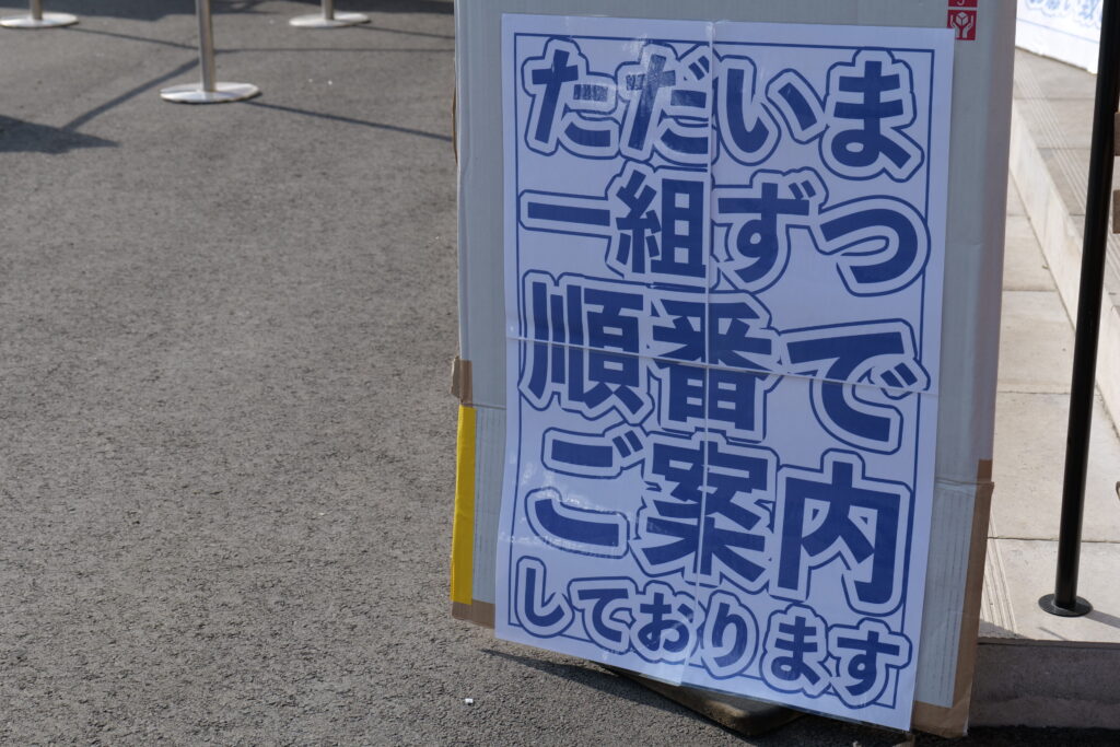 うおまさ特設会場の受付窓口イメージ。スタッフが恵方巻をお渡ししている様子。