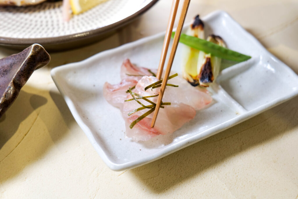 寒平目の昆布締めを箸で持ち上げた一口。食感と旨みが伝わるカット（魚政（うおまさ））