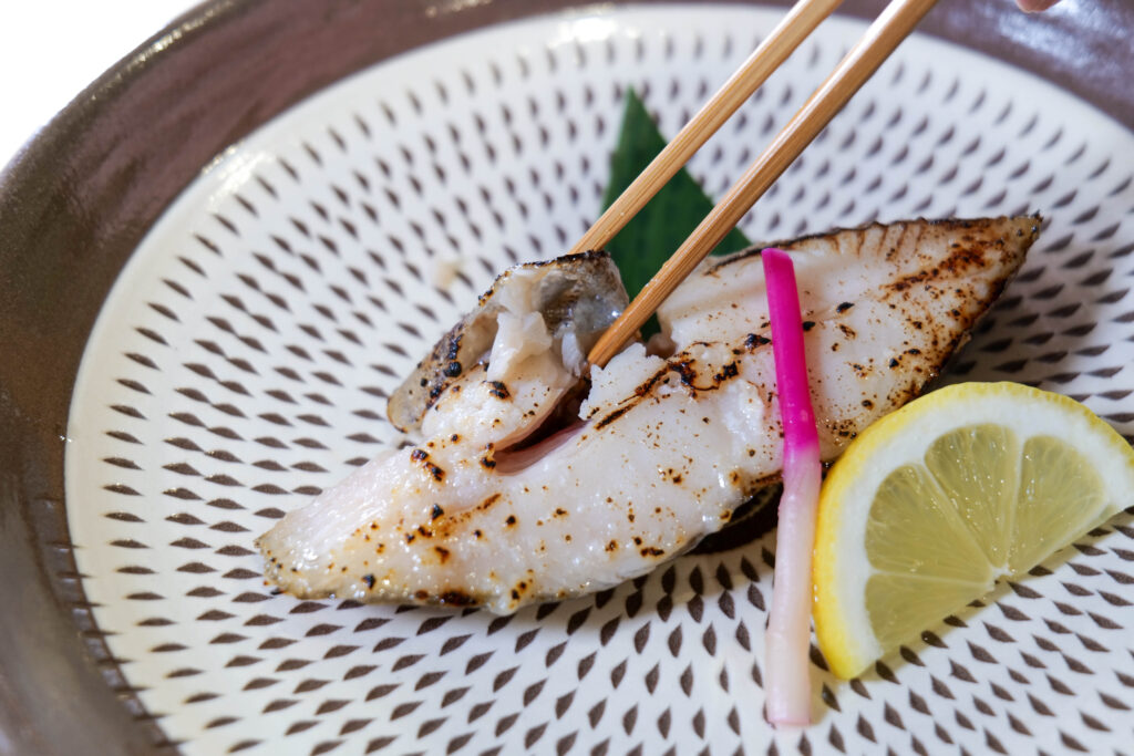 塩麹焼きを箸で持ち上げた一口。ふっくら感が伝わるカット（魚政（うおまさ））
